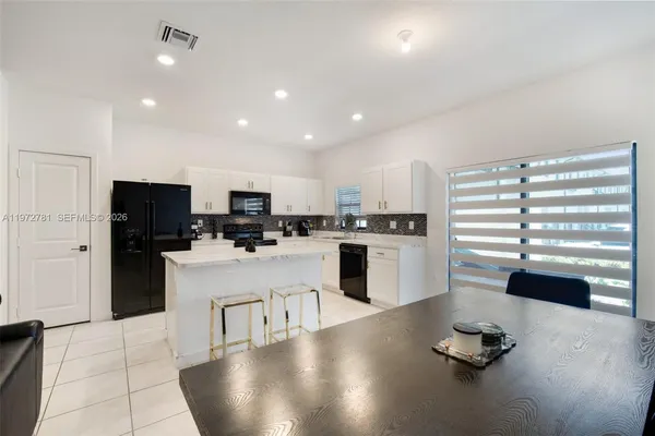 a room with stainless steel appliances kitchen island granite countertop a refrigerator a stove and a sink with granite countertops
