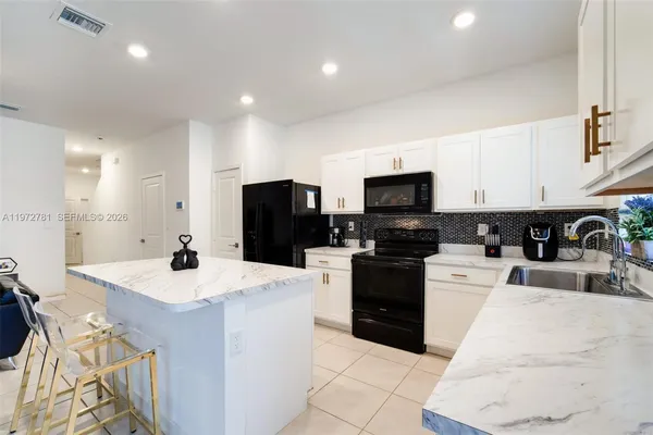 a kitchen with stainless steel appliances kitchen island sink refrigerator and microwave