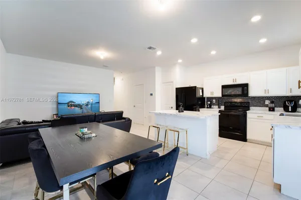 a living room with stainless steel appliances furniture and a flat screen tv
