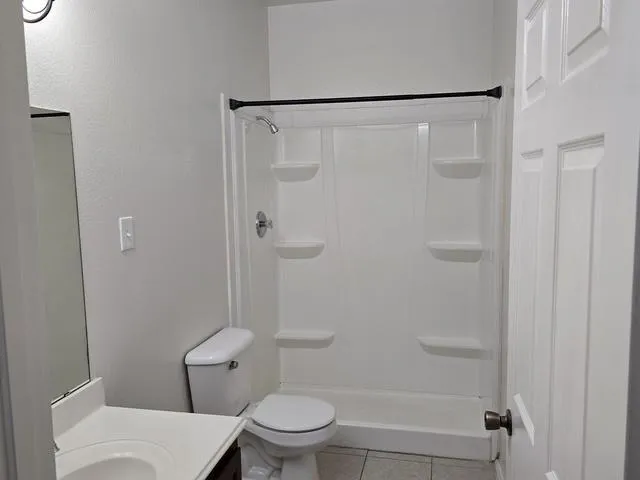a white toilet sitting next to a shower