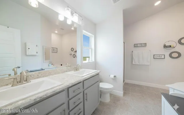 a bathroom with a double vanity sink toilet and a mirror