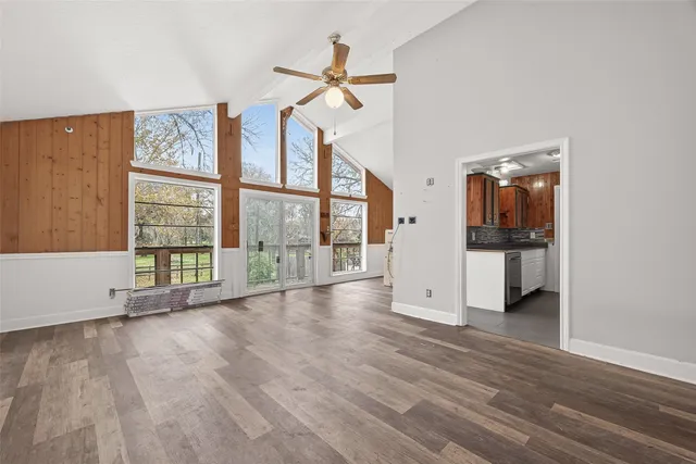 a view of an empty room with a window and wooden floor
