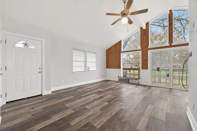 a view of an empty room with a window and wooden floor