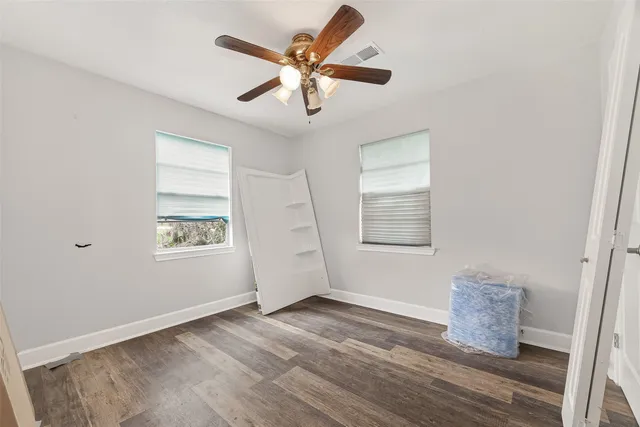 an empty room with windows and fan