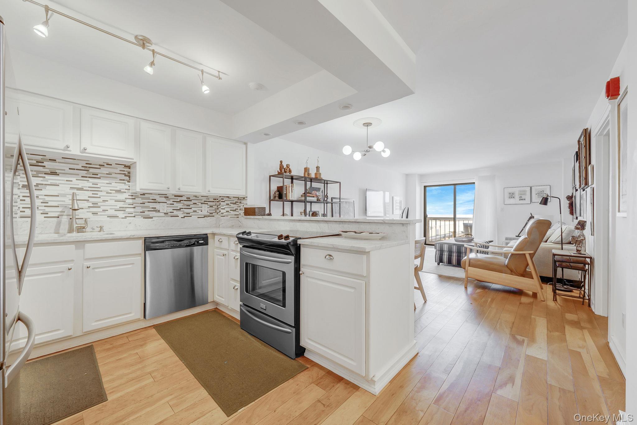 360 Shore Road, Unit 3H Long Beach, NY 11561 - Photo 23 of 23 a kitchen with a sink dishwasher stove and white cabinets with wooden floor