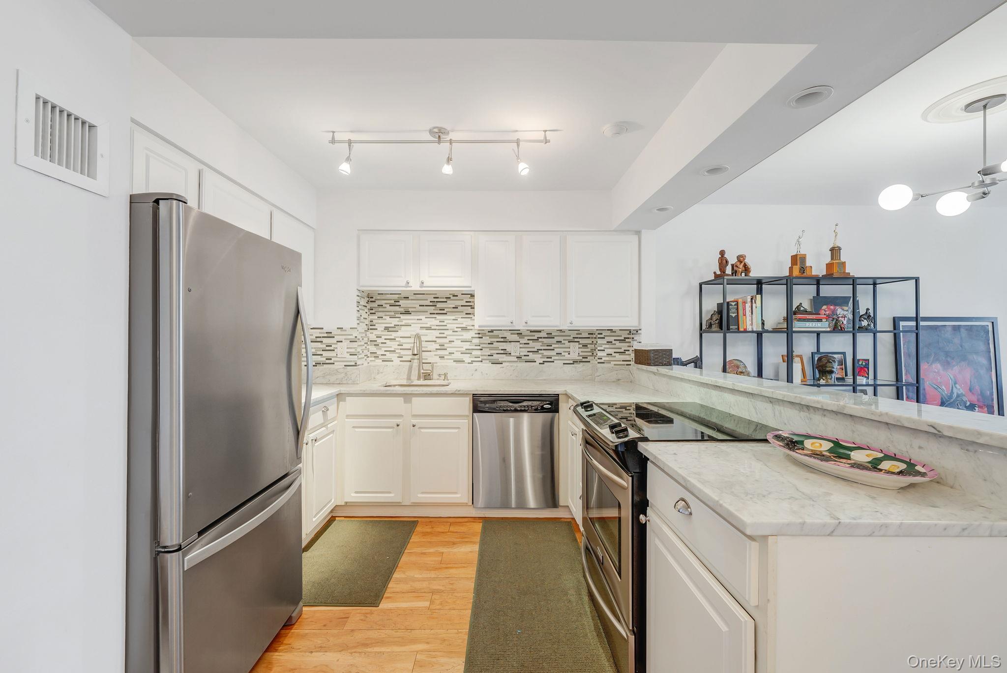 360 Shore Road, Unit 3H Long Beach, NY 11561 - Photo 9 of 23 a kitchen with a refrigerator sink and cabinets