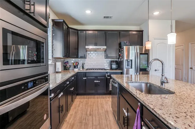 a kitchen with stainless steel appliances granite countertop a sink stove and refrigerator