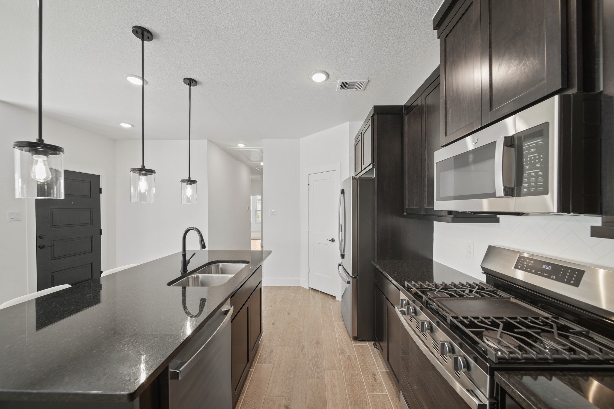 10111 Crescendo Way Manvel, TX 77578 - Photo 16 of 25 a kitchen with stainless steel appliances granite countertop a sink a stove and a refrigerator