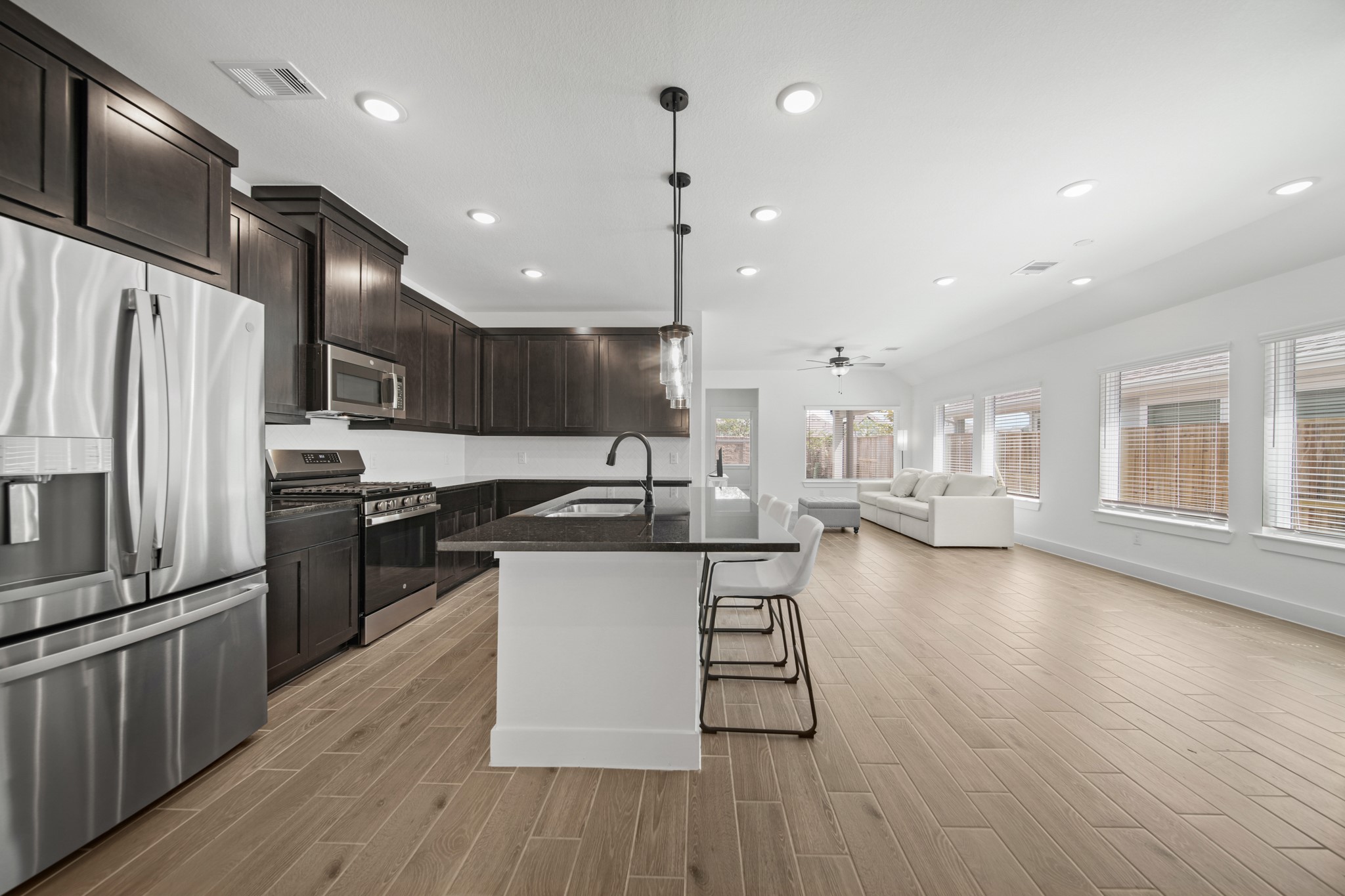 10111 Crescendo Way Manvel, TX 77578 - Photo 5 of 25 a kitchen with stainless steel appliances kitchen island granite countertop a stove a sink a refrigerator and a microwave