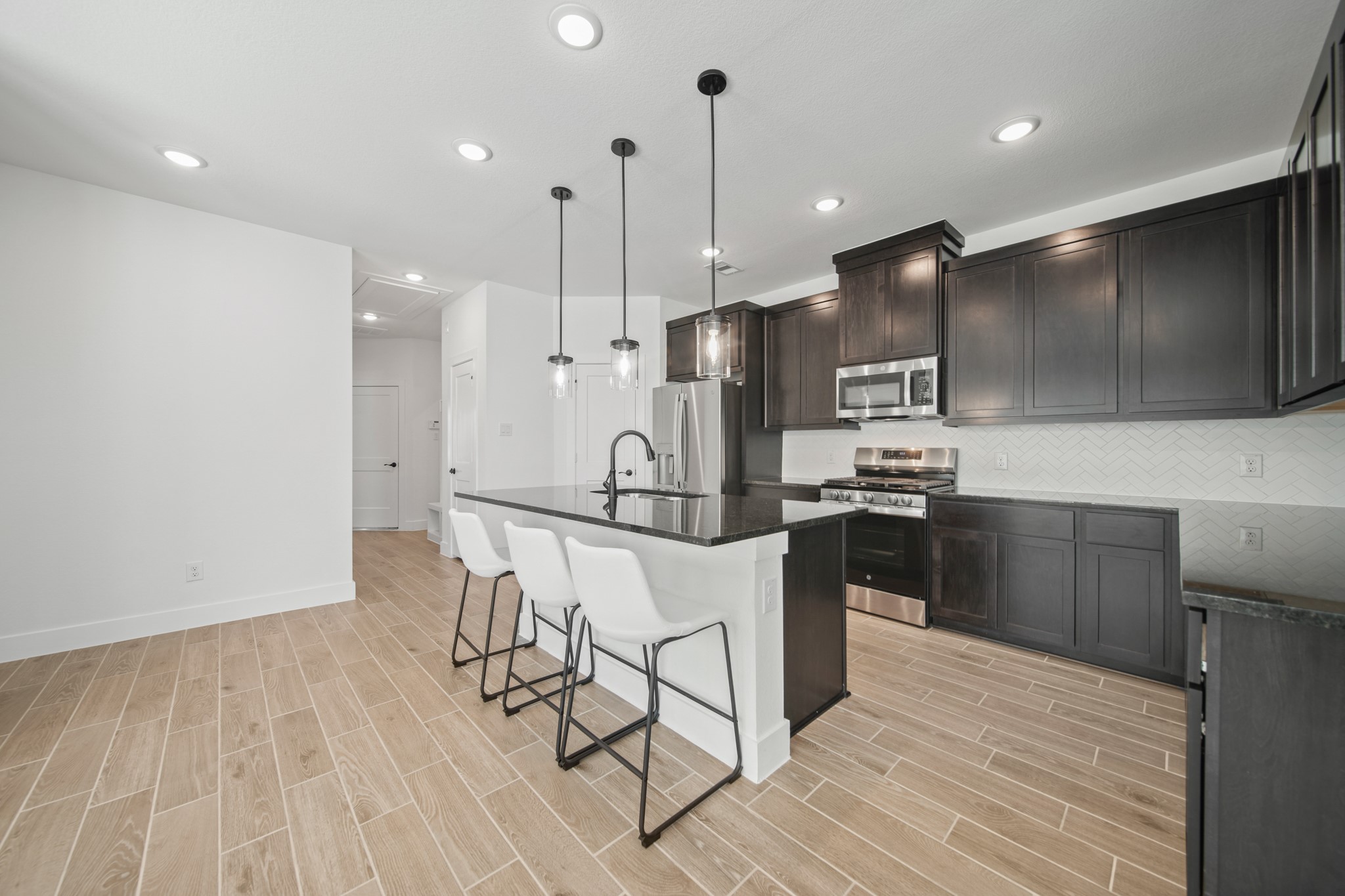 10111 Crescendo Way Manvel, TX 77578 - Photo 6 of 25 a kitchen with stainless steel appliances kitchen island granite countertop a refrigerator a stove a microwave oven a sink with island and chairs with wooden floor