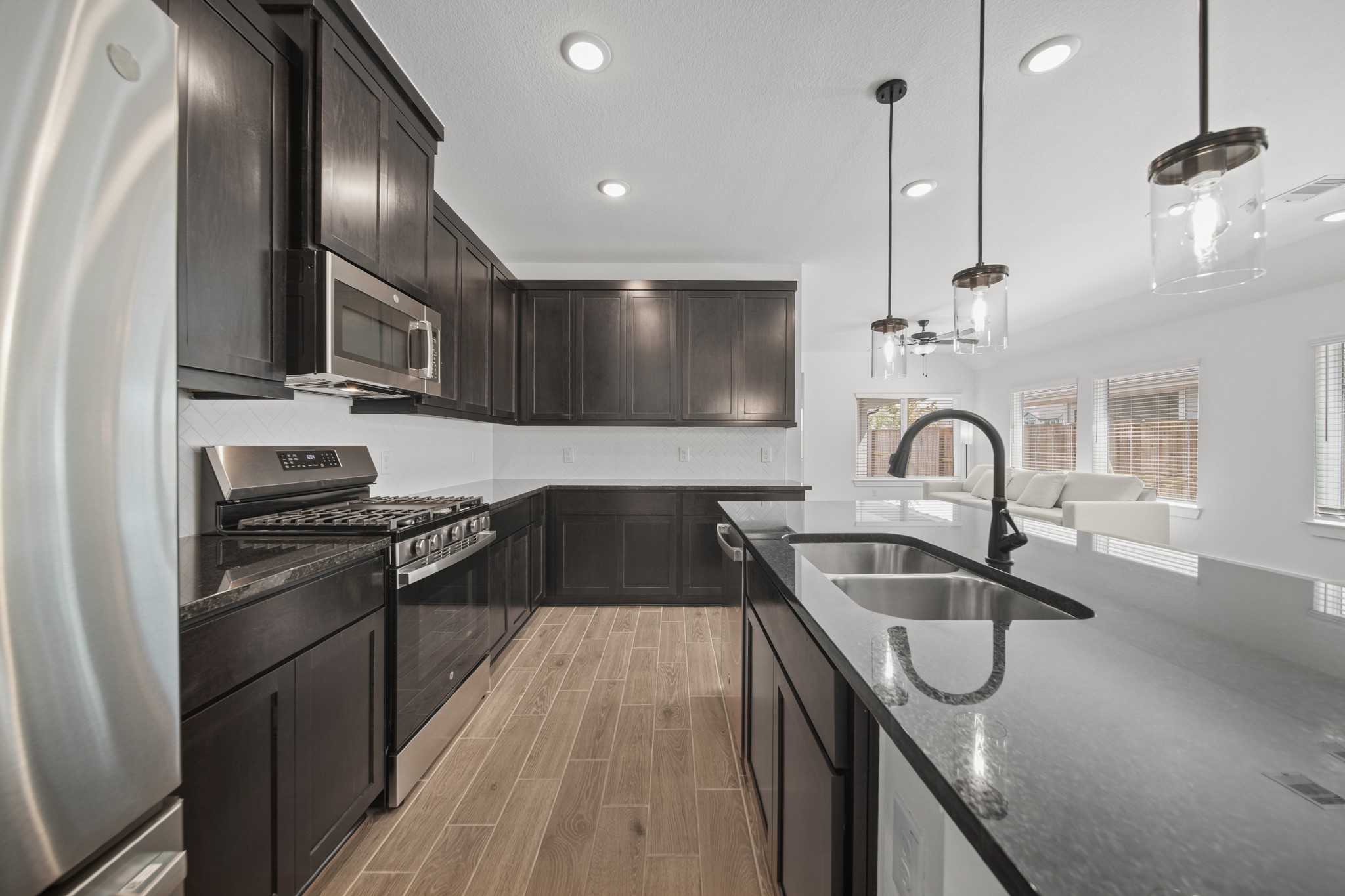 10111 Crescendo Way Manvel, TX 77578 - Photo 7 of 25 a kitchen with kitchen island granite countertop a sink stainless steel appliances and cabinets