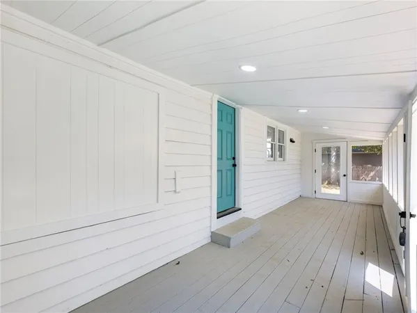 a view of hallway with window and wooden floor