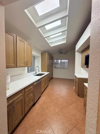 a large kitchen with a large counter top space a sink a window and stainless steel appliances