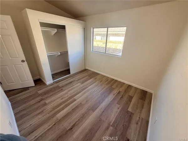 an empty room with wooden floor cabinet and window