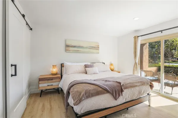 a bedroom with a bed wooden floor and a large window