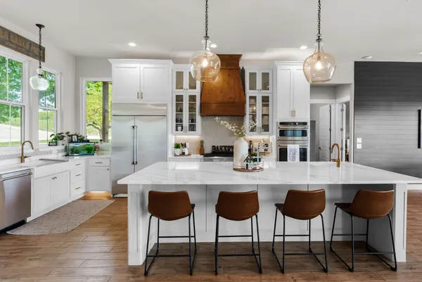 a kitchen with stainless steel appliances granite countertop a sink a stove a refrigerator and island with wooden floor