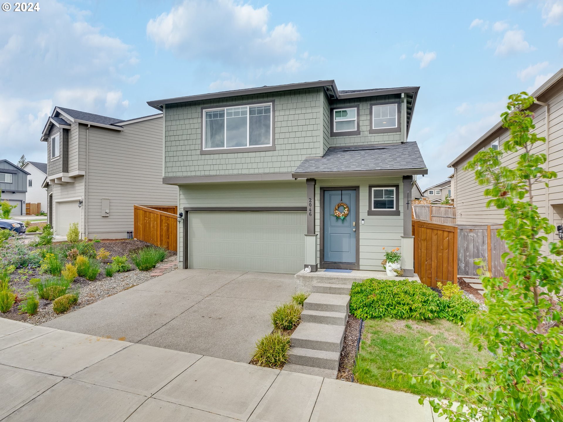 2046 South Meadowlark Dr. Loop Ridgefield, WA 98642 - Photo 3 of 38 a front view of a house with a garden and trees