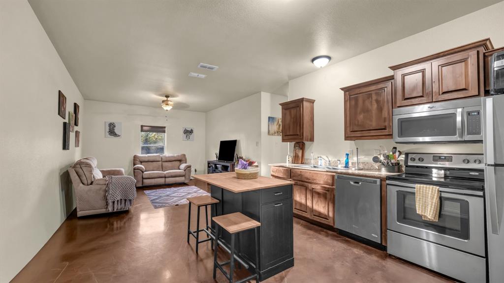 120 Bunkhouse Road Stephenville, TX 76401 - Photo 8 of 40 a kitchen with stainless steel appliances granite countertop a stove top oven a sink dishwasher a dining table and chairs with wooden cabinets