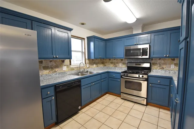 a kitchen with granite countertop wooden cabinets stainless steel appliances and a window