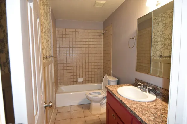 a bathroom with a granite countertop sink a toilet a mirror a bathtub and shower