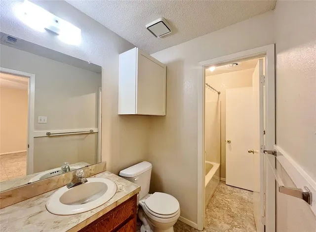 a bathroom with a granite countertop sink toilet a mirror and shower