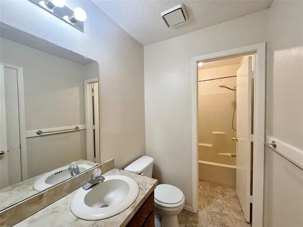 a bathroom with a granite countertop toilet a sink and a mirror