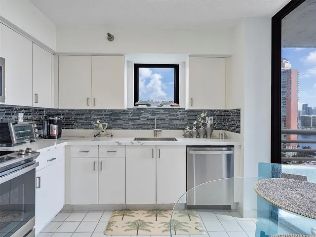 a kitchen with granite countertop white cabinets sink and stainless steel appliances
