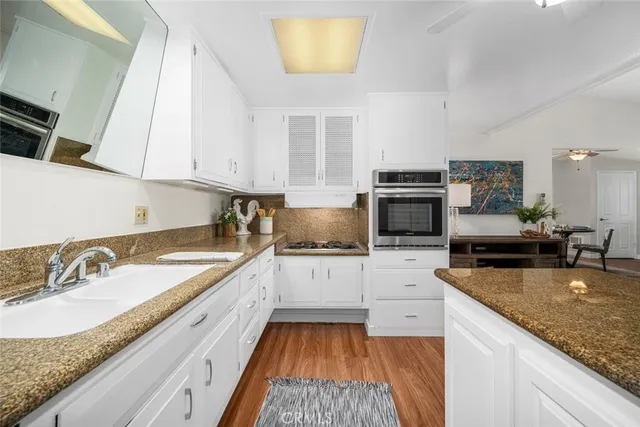 a kitchen with granite countertop a sink stove and cabinets