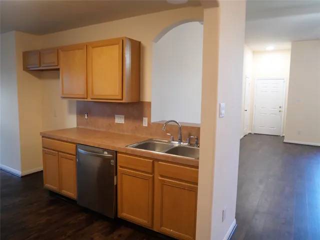 a kitchen with stainless steel appliances granite countertop a sink and cabinets with wooden floor