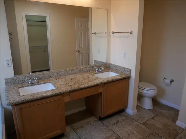 a bathroom with a granite countertop sink toilet and mirror