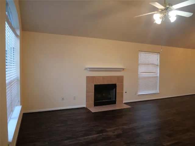 a view of a livingroom with wooden floor a ceiling fan and a fireplace