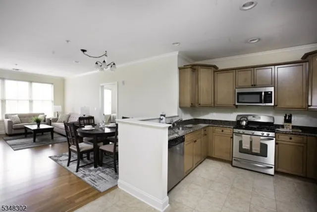 a kitchen with stainless steel appliances granite countertop a stove top oven a sink dishwasher a dining table and chairs with wooden floor