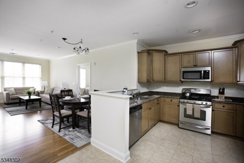 545 Morris Avenue, Unit 213 Summit, NJ 07901 - Photo 2 of 8 a kitchen with stainless steel appliances granite countertop a stove top oven a sink dishwasher a dining table and chairs with wooden floor