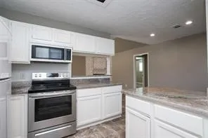 a kitchen with granite countertop white cabinets and stainless steel appliances