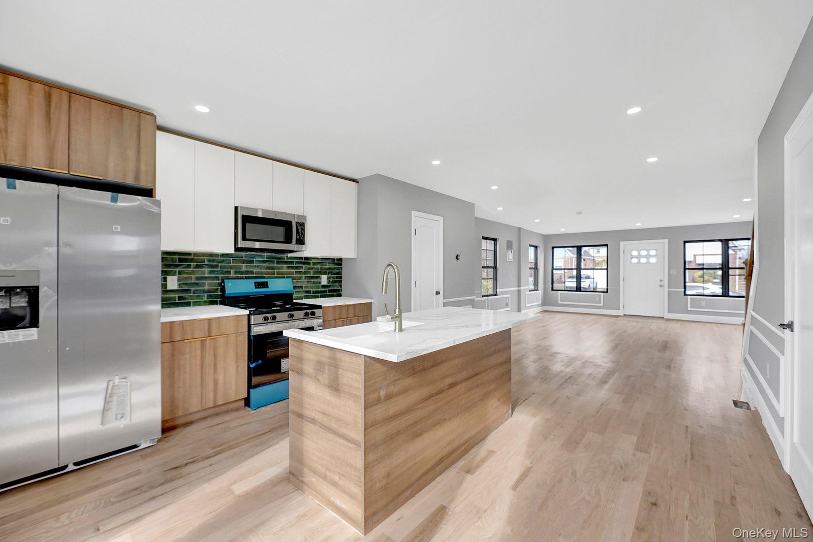 a large kitchen with a center island wooden floor stainless steel appliances and cabinets
