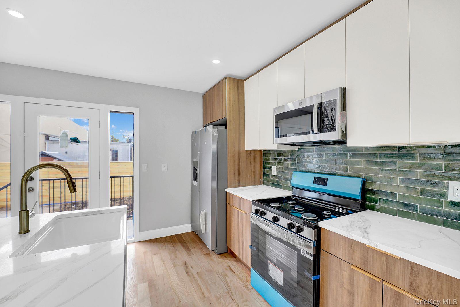 217-14 133rd Road Queens, NY 11413 - Photo 5 of 32 a kitchen with stainless steel appliances a stove top oven a sink a refrigerator a microwave and cabinets