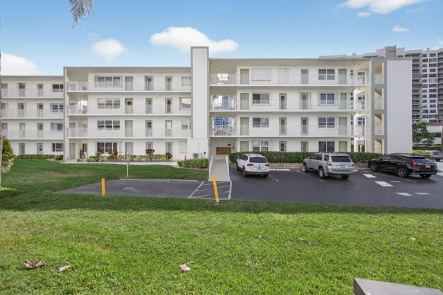 a view of a house with a yard and table and chairs under an umbrella