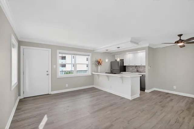 a large white kitchen with white cabinets and wooden floor