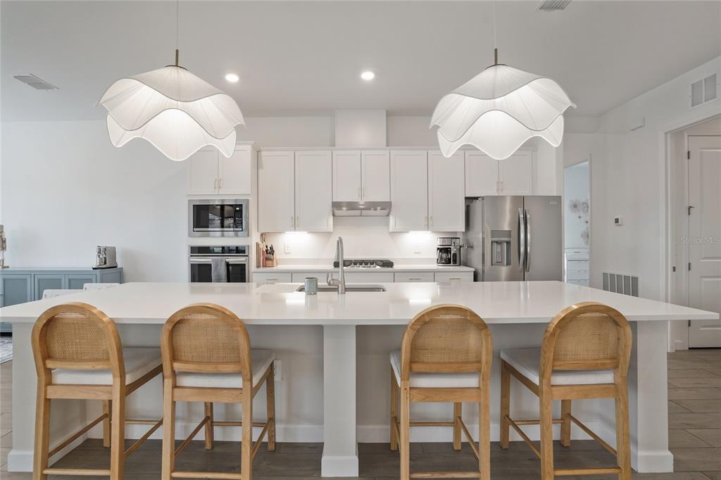 15906 Tradewind Terrace Lakewood Ranch, FL 34211 - Photo 7 of 67 a kitchen with stainless steel appliances granite countertop a table chairs and a refrigerator