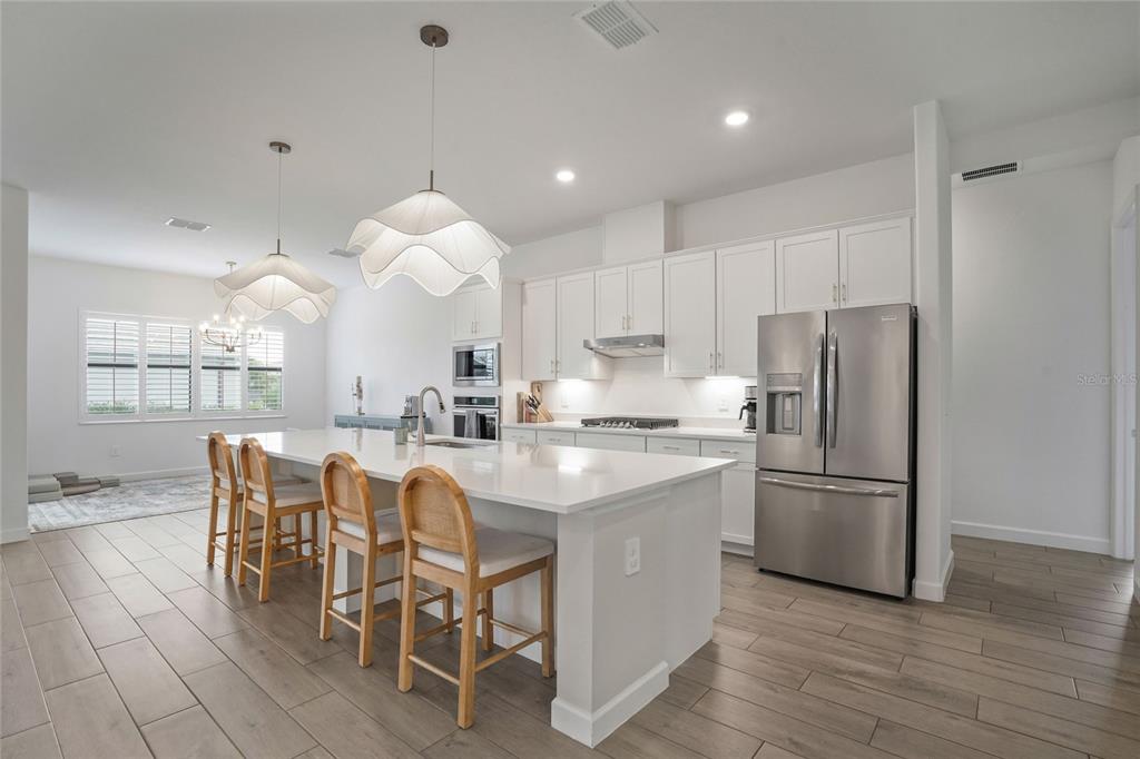 15906 Tradewind Terrace Lakewood Ranch, FL 34211 - Photo 9 of 67 a kitchen with stainless steel appliances granite countertop a table chairs and a refrigerator