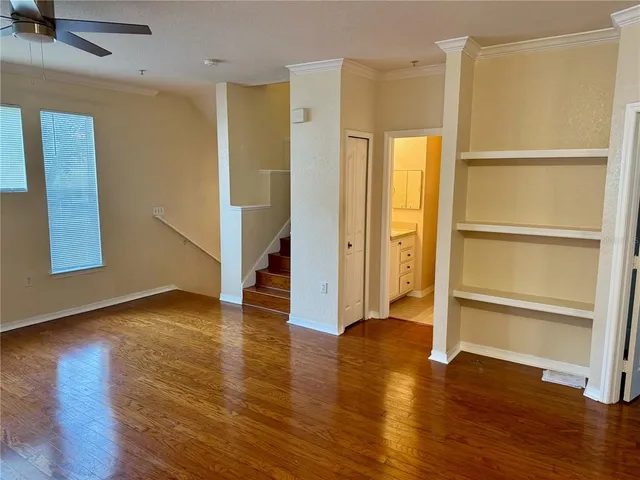 a view of an empty room with wooden floor and a window