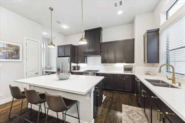 a kitchen with a sink a stove a refrigerator and chairs