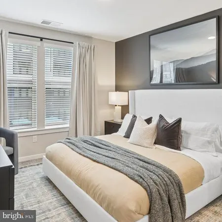 a bedroom with bed and a large mirror next to a window