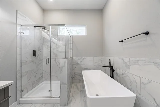 a bathroom with a white bath tub sitting next to a shower