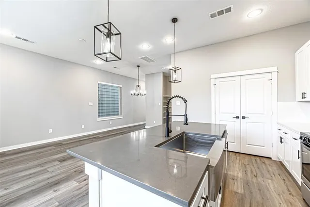 a kitchen with stainless steel appliances granite countertop a sink a stove and a wooden floors
