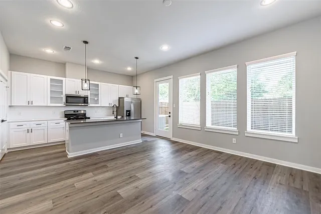 a large kitchen with stainless steel appliances granite countertop a large counter top a stove and a wooden floors