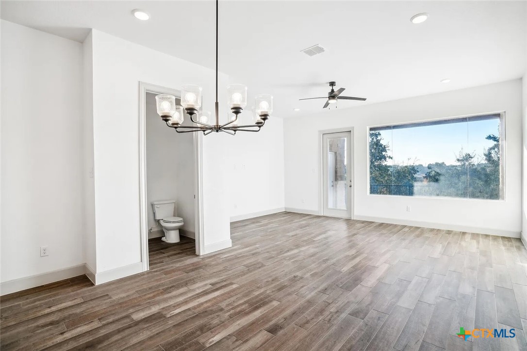 289 Star Grass, Unit 3 Spring Branch, TX 78070 - Photo 13 of 40 a view of a room with wooden floor and a ceiling fan
