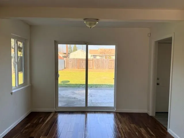 a view of an empty room with wooden floor and a window