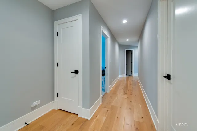 a view of a hallway with wooden floor and a bathroom