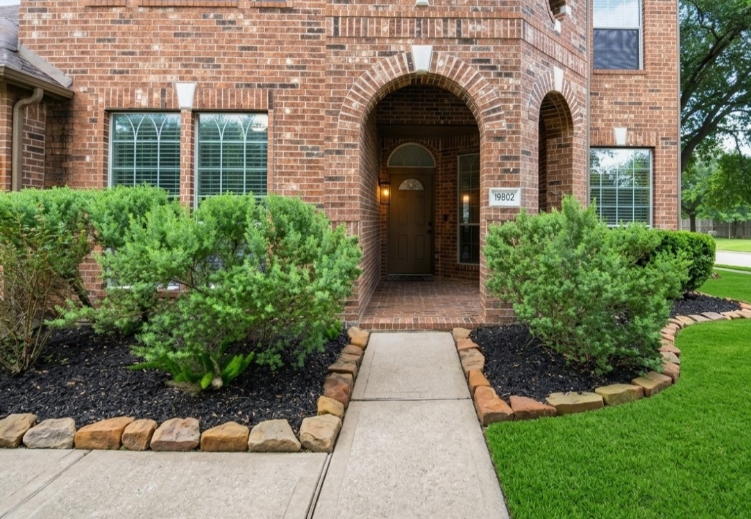 19802 Shavon Springs Drive Spring, TX 77388 - Photo 3 of 30 Welcoming brick entrance framed by lush greenery, leading to a charming archway and front door.